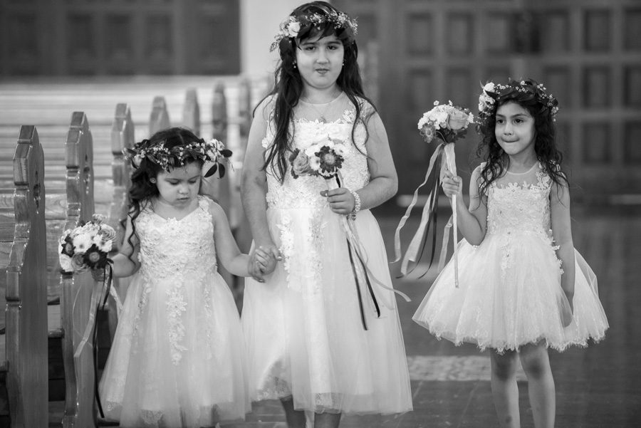 Three young flower girls walking down the aisle at St Timothy's Catholic church